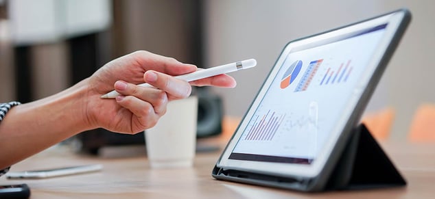 person pointing stylus at ipad of financial charts