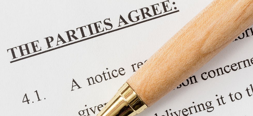 Closeup of a legal contract with a wooden pen laid on top