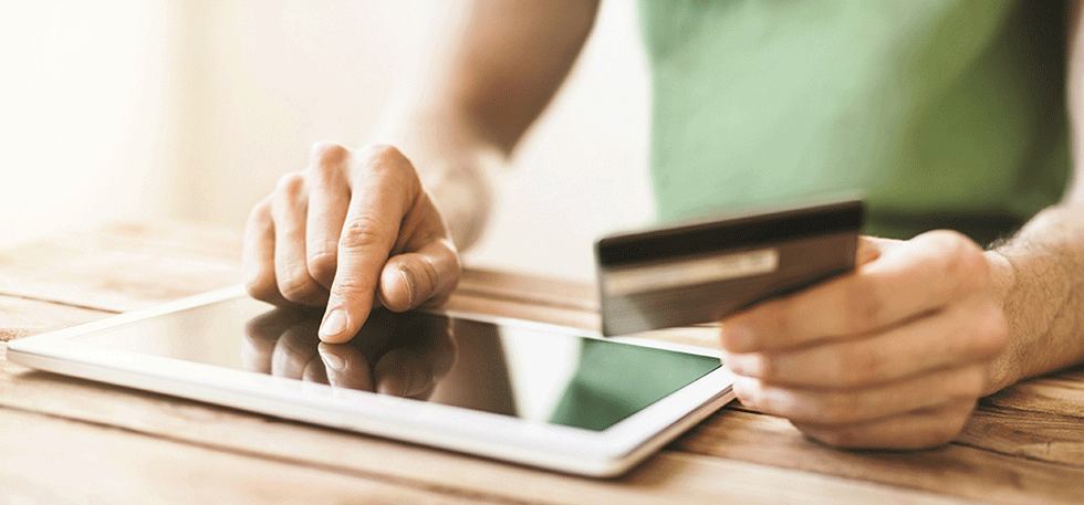 person holding a credit card while tapping an tablet