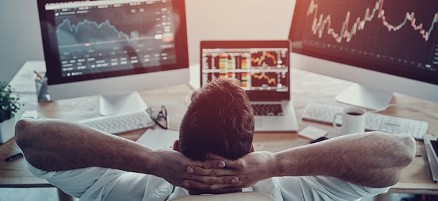 Young man leaning back looking at investment stock_GettyImages_9800x450